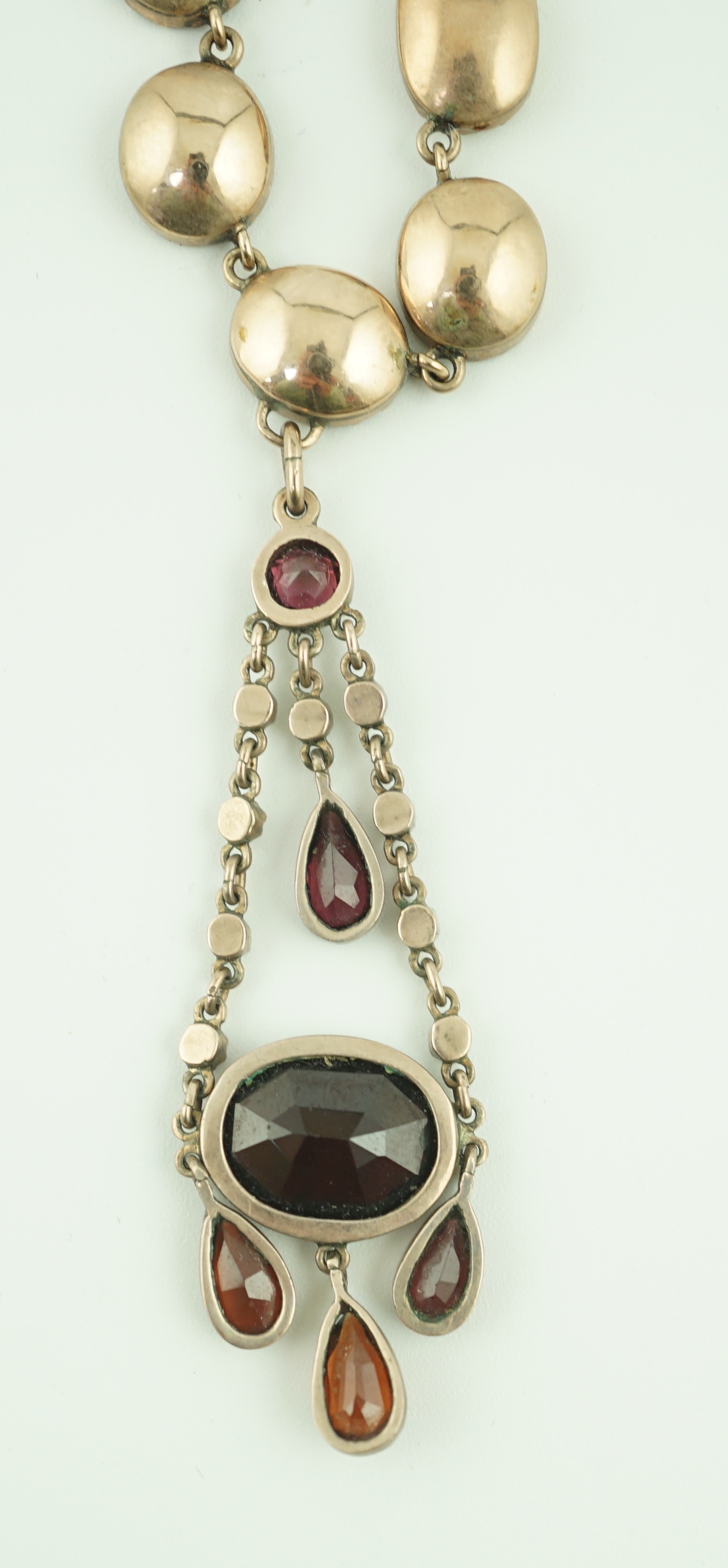 An early 19th century gold, and thirty five graduated foil backed garnet set necklace, with later garnet and seed pearl set drop